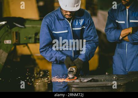 Industrial Worker Using Angle Grinder and Cutting a Metal Sheet. Contractor in Safety Uniform and Hard Hat Manufacturing Metal Structures.Heavy Indust Stock Photo