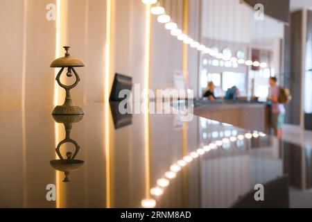 Antique silver front desk call bell on reception counter. Modern luxury hotel desk in pastel beige color background. Stock Photo