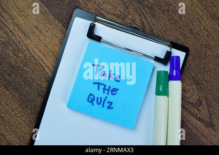 Concept of Take the Quiz write on sticky notes isolated on Wooden Table. Stock Photo
