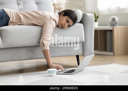 Overworked exhausted Indian freelancer woman lying on sofa Stock Photo