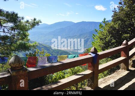 View of the Paro Valley from the trail to the Tiger's Nest Monastery in the Kingdom of Bhutan. A wooden fence and prayer flags are in the foreground Stock Photo