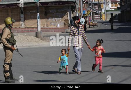 Bilder des Tages (170529) -- SRINAGAR, May 29, 2017 -- A man and children walks past an Indian paramilitary trooper during curfew-like restrictions in downtown Srinagar, summer capital of Indian-controlled Kashmir, May 29, 2017. Curfew-like restrictions have been imposed in several areas of Srinagar to prevent protests and clashes. ) (zcc) KASHMIR-SRINAGAR-RESTRICTIONS JavedxDar PUBLICATIONxNOTxINxCHN   Images the Day  Srinagar May 29 2017 a Man and Children Walks Past to Indian paramilitary Trooper during Curfew Like Restrictions in Downtown Srinagar Summer Capital of Indian Controlled Kashmi Stock Photo