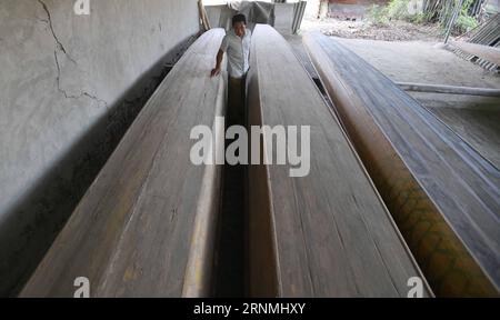 (170530) -- CHENGDU, May 30, 2017 -- Jiang Zhiquan examines the bottom of dragon boat in Xinjin County of Chengdu City, southwest China s Sichuan Province, May 25, 2017. Jiang Zhiquan, 63, is a villager of Yangpai Village of Xinjin County of Chengdu City. His family has been engaged in building dragon boats for three generations. Jiang inherited the handicraft and has built dragon boats for more than 40 years. To build a dragon boat is not complicated, but every step must be exquisite in workmanship. Timber should be chipped to be smooth boards to make hull and bottom of a boat. A dragon boat Stock Photo