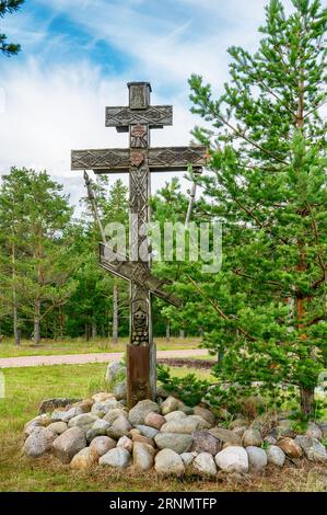 Old wooden cross on the island of Konevets on the shore of Lake Ladoga. The symbol of the monastic feat in a secluded monastery. Stock Photo