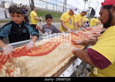 (170611) -- LOS ANGELES, June 11, 2017 -- Volunteers work on a pizza as they broke the Guinness World Records title for the longest pizza with a length of 1.32 miles (2.13 kilometers) in Fontana, the United Staes, June 10, 2017. The last longest pizza measured 1,853.88 meters and was achieved by Napoli Pizza Village, in Naples, Italy, May 18, 2016. ) (gj) U.S.-LOS ANGELES-LONGEST PIZZA ZhaoxHanrong PUBLICATIONxNOTxINxCHN   170611 Los Angeles June 11 2017 Volunteers Work ON a Pizza As They Broke The Guinness World Records Title for The LONGEST Pizza With a length of 1 32 Miles 2 13 Kilometers i Stock Photo