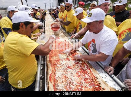 (170611) -- LOS ANGELES, June 11, 2017 -- Volunteers work on a pizza as they broke the Guinness World Records title for the longest pizza with a length of 1.32 miles (2.13 kilometers) in Fontana, the United Staes, June 10, 2017. The last longest pizza measured 1,853.88 meters and was achieved by Napoli Pizza Village, in Naples, Italy, May 18, 2016. ) (gj) U.S.-LOS ANGELES-LONGEST PIZZA ZhaoxHanrong PUBLICATIONxNOTxINxCHN   170611 Los Angeles June 11 2017 Volunteers Work ON a Pizza As They Broke The Guinness World Records Title for The LONGEST Pizza With a length of 1 32 Miles 2 13 Kilometers i Stock Photo