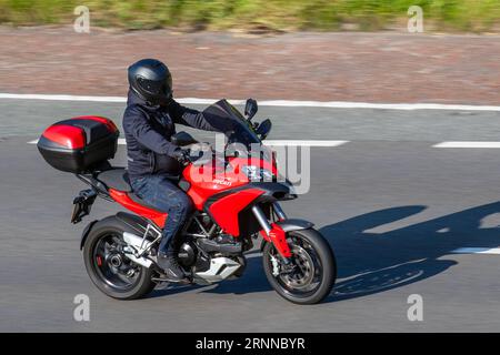 Red Ducati 950 S Supersport motorcycle travelling at speed on the M6 motorway in Greater Manchester, UK Stock Photo