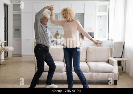 Excited old mature energetic couple in love dancing at home Stock Photo