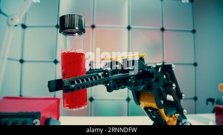 a robot holds a sample of a chemical substance the concept of using robotics in laboratory work Stock Photo