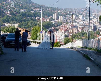 Wedding couple being photographed on a steep road over looking the city of Sarajevo, Bosnia and Herzegovina, September 02, 2023 Stock Photo