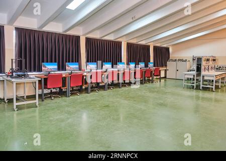 empty computer lab in a university. Computer lab room. room with a lot of computers, desks, chairs, and keyboards. red seats. Stock Photo