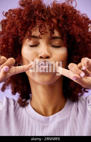 Face, beauty and lips of a woman with a digital eye mask for skincare in studio on a purple background. Hands, fingers and mouth with a young model Stock Photo