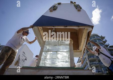 (170728) -- VANCOUVER, July 28, 2017 -- Workers place an ice box structure onto the ice block during the Ice Box Challenge in Vancouver, Canada, July 27, 2017. The Ice Box Challenge is a public experiment to demonstrate the benefits of super energy-efficient buildings under the passive house construction standard. Two small house-like boxes built with passive house standard and local building code specifications sitting side-by-side under open area for 18 days with a one-tonne block of ice encased in order to testify the new zero emission building standard.) CANADA-VANCOUVER-ICE BOX CHALLENGE Stock Photo