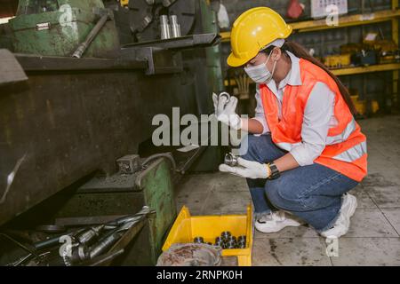 Asian woman worker working in heavy metal industry workshop wearing facemask for hygiene healthy safety Stock Photo