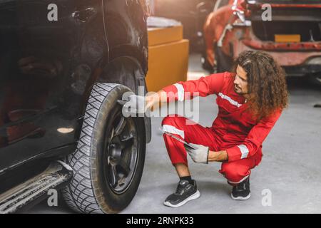 auto service male working in garage car workshop looking check repair broken tire with tablet computer Stock Photo