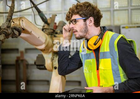 smart young engineer work service maintenace programming automatic robot welding machine in heavy metal automation factory Stock Photo