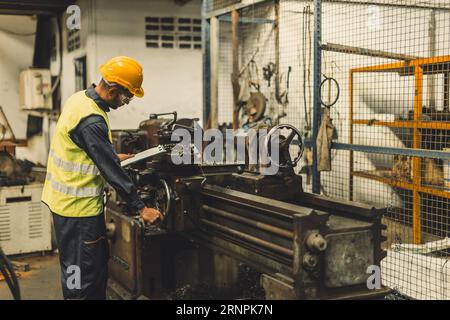 Hispanic Latin Indian male professional tecnician worker working with steel precision milling machine in lathe metal factory Stock Photo