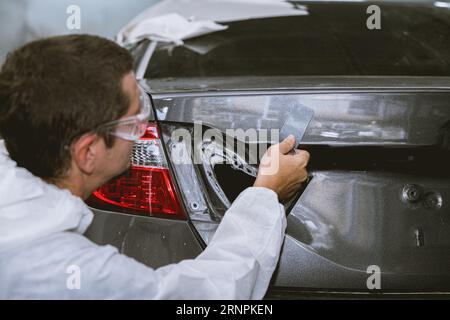 car body painter painting select paint colors using sample card for pick choice color shade in auto garage body workshop Stock Photo