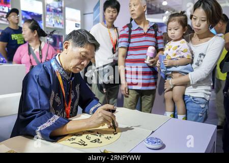 (170912) -- BEIJING, Sept. 12, 2017 -- Wei Zonglin (L front), a professor from Guizhou Minzu University, writes characters of the Shui ethnic group at the first China Beijing International Language & Culture Expo (ILCE) in Beijing, capital of China, Sept. 12, 2017. The first China Beijing ILCE would be held here from Sept. 11 to 13. )(wjq) CHINA-BEIJING-LANGUAGE & CULTURE EXPO (CN) ShenxBohan PUBLICATIONxNOTxINxCHN Stock Photo