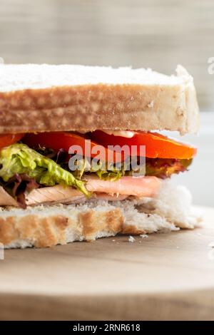 A close up of the fresh filling of a ham and salad sandwich with tomato, ham, salad and mayo on sliced white sourdough bread with copy space Stock Photo