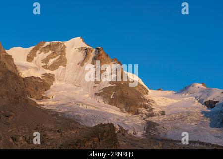 Gran Paradiso mountain and glacier view from chabod hut at sunset. golden hour, colored peak against blue sky. landscape Stock Photo