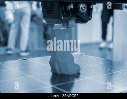 3D printer printing prototype of toy from molten plastic. Process of creating prototype model of toy on 3D printer from yellow melted plastic close-up. Additive new printer technology. Modern printing Stock Photo