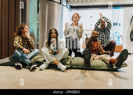 Happy, overjoyed, multiracial colleagues playing electronic games at work while taking a break. Men celebrating a win Stock Photo