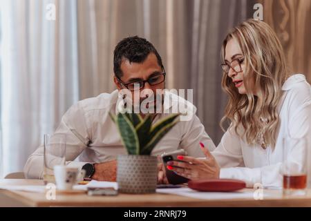 Two middle-aged business leaders discussing company work efficiency and profit growth while sitting at the cafe Stock Photo