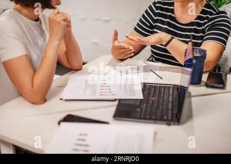 Two businesswomen discussing about their sales in the last month at the office Stock Photo