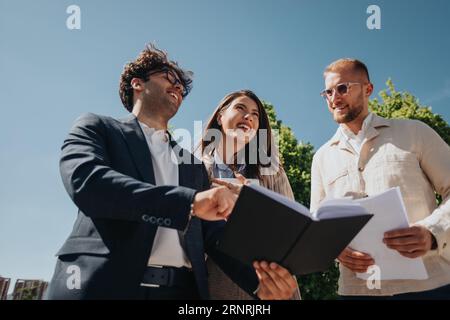 Young business people having fun conversation and smiling while working together, discussing paperwork, reports and planning new business projects Stock Photo