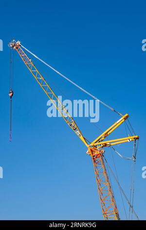 Detail of construction crane on building site, isolated against blue sky. Stock Photo