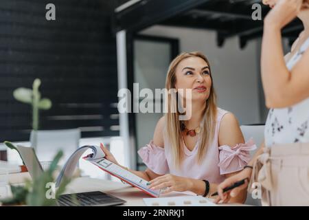 Happy, satisfied, senior businesswoman reading and analyzing her colleague work, positive results or achievements. Stock Photo