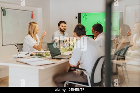 A diverse group of professionals collaborate in a modern meeting room, discussing strategies, sharing ideas, and prioritizing objectives for business Stock Photo