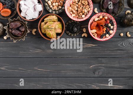 Dried raw organic dates dried fruits nuts lukum baklava black wooden table Stock Photo