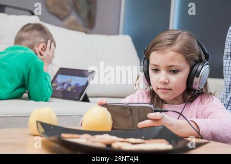 Kids using technologies living room Stock Photo