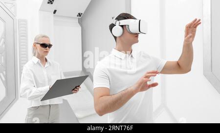 Young man with virtual reality simulator woman testing Stock Photo