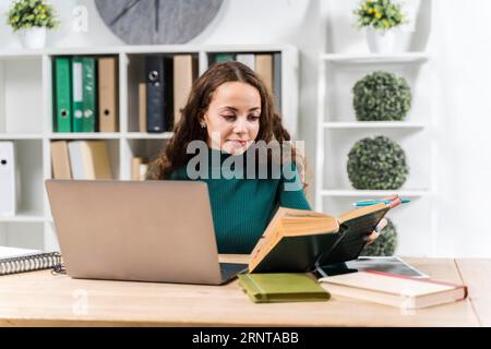 Medium shot smiley girl studying with dictionary laptop Stock Photo