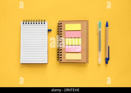 High angle view spiral notepad adhesive notes pen yellow background Stock Photo