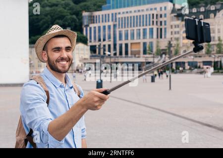 Portrait happy young man carrying backpack taking selfie with smartphone Stock Photo