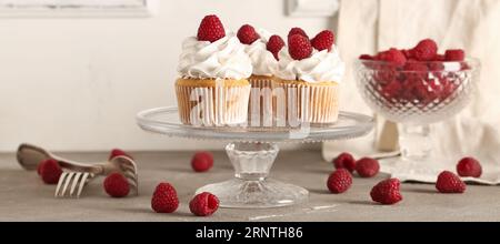Stand with tasty raspberry cupcakes on table Stock Photo