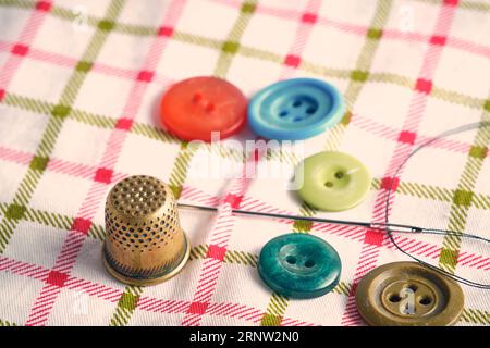 Sewing kit consisting needle, thimble and buttons fabric background Stock Photo