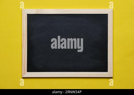 Black blackboard for notes in wooden frame yellow background Stock Photo