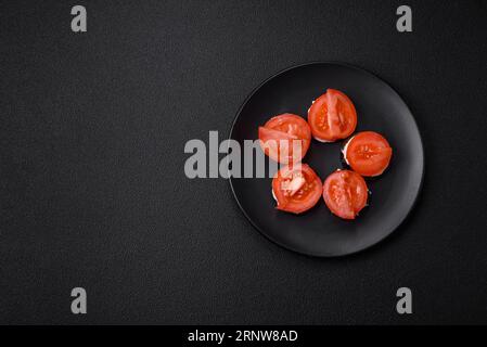 Delicious eggplant cut into circles grilled and cooked with mayonnaise and tomatoes on a dark concrete background Stock Photo
