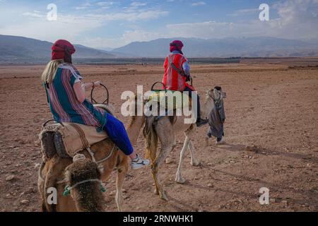 Marrakech, Morocco - Feb 22, 2023: Tourists ride Dromedary camels through the Agafay desert Stock Photo