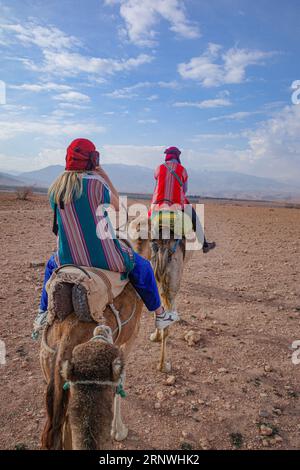 Marrakech, Morocco - Feb 22, 2023: Tourists ride Dromedary camels through the Agafay desert Stock Photo