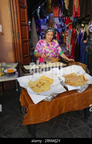 Marrakech, Morocco - Feb 21, 2023: A lady makes fresh flat bread on a market stall in Marrakech Medina Stock Photo
