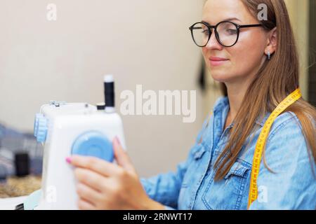 Beautiful young woman sewing clothes using a sewing machine Stock Photo