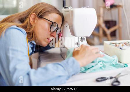 Beautiful young woman sewing clothes using a sewing machine Stock Photo