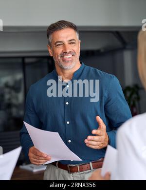Happy mature executive manager discussing documents with business team. Stock Photo