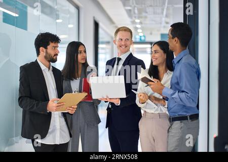 Happy diverse professional team young business people talking in office hallway. Stock Photo